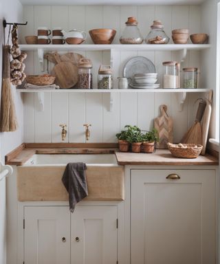 A kitchen utility room with a Belfast style sink in stone, and open shelving above