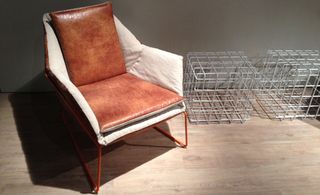 Light natural wood floor, whitge wall, brown and cream leather chair with brown metal frame. two small silver metal crates at the right of the chair