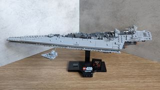 A Lego Star Wars Executor Super Star Destroyer build, displayed on a wooden surface against a grey background.
