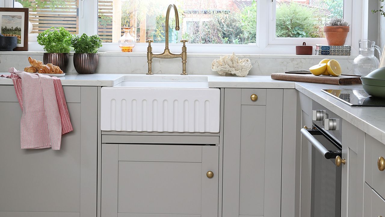 Grey shaker kitchen with white belfast sink and gold knob handles.