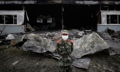 A policeman stands guard outside the burned out poultry slaughterhouse 