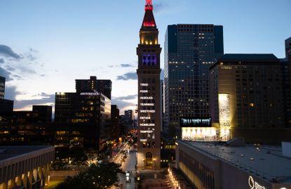 image with multiple buildings with the focus on a building lit up with 9 different words 