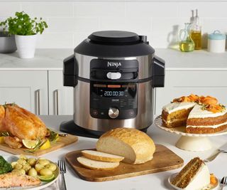 Ninja Foodi 15-in-1 Air Fryer on a kitchen counter, surrounded by plates of air-fried food.