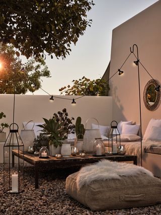 courtyard space at dusk with floor cushions, lanterns and garden lighting