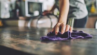 Woman wiping down table at home