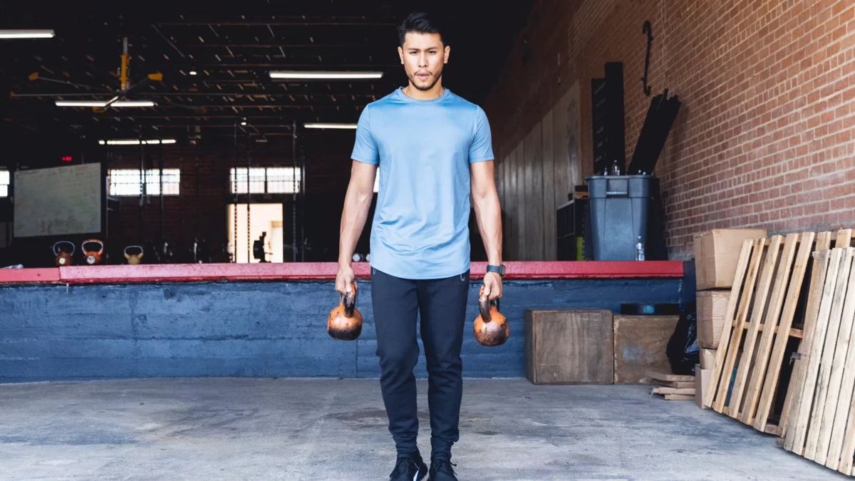 Man performing a farmer&#039;s hold with two kettlebells holding one in each hand