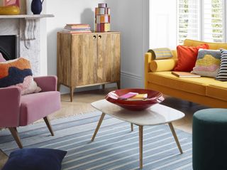 mid-century style living room with a yellow sofa, pink armchair and wooden coffee table