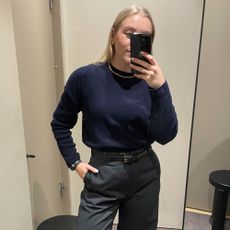 woman wears navy jumper, tailored trousers