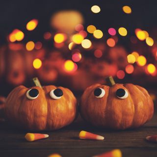 pumpkins with googley eyes with an orange sparkly background and candy corn