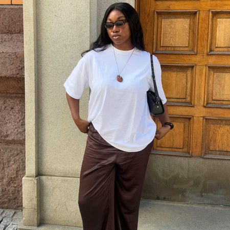 Nnenna in a white T-shirt and brown satin trousers