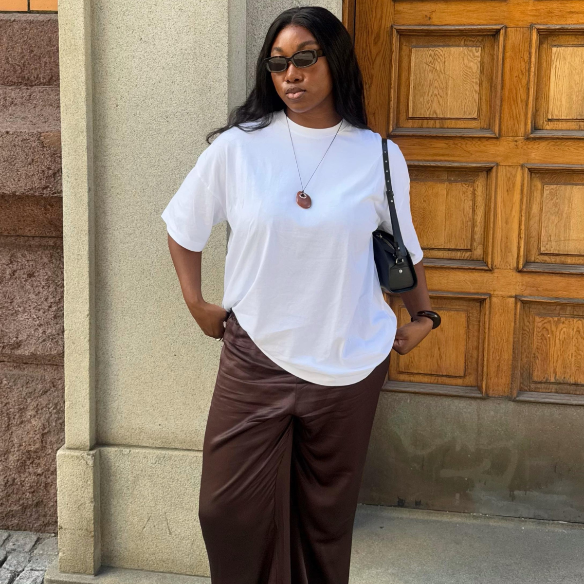 Nnenna in a white T-shirt and brown satin trousers
