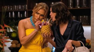 Jennifer Lopez and Callie Hernandez in Shotgun Wedding drinking cocktails from a pineapple