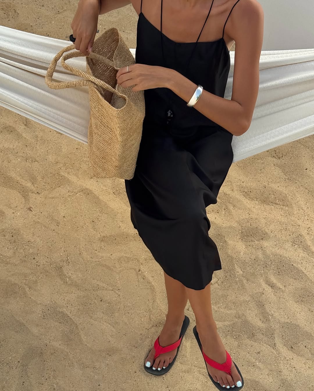Salome in red-and-black flip-flops and black dress with silver bangle