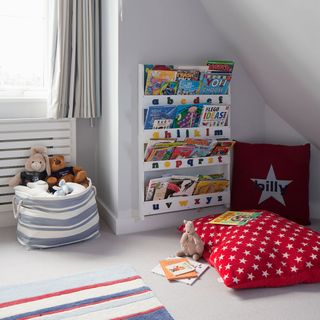 white wall room with book shelve red cushions books and teddies