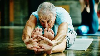 Man showing off his range of motion in seated forward bend pose during yoga class