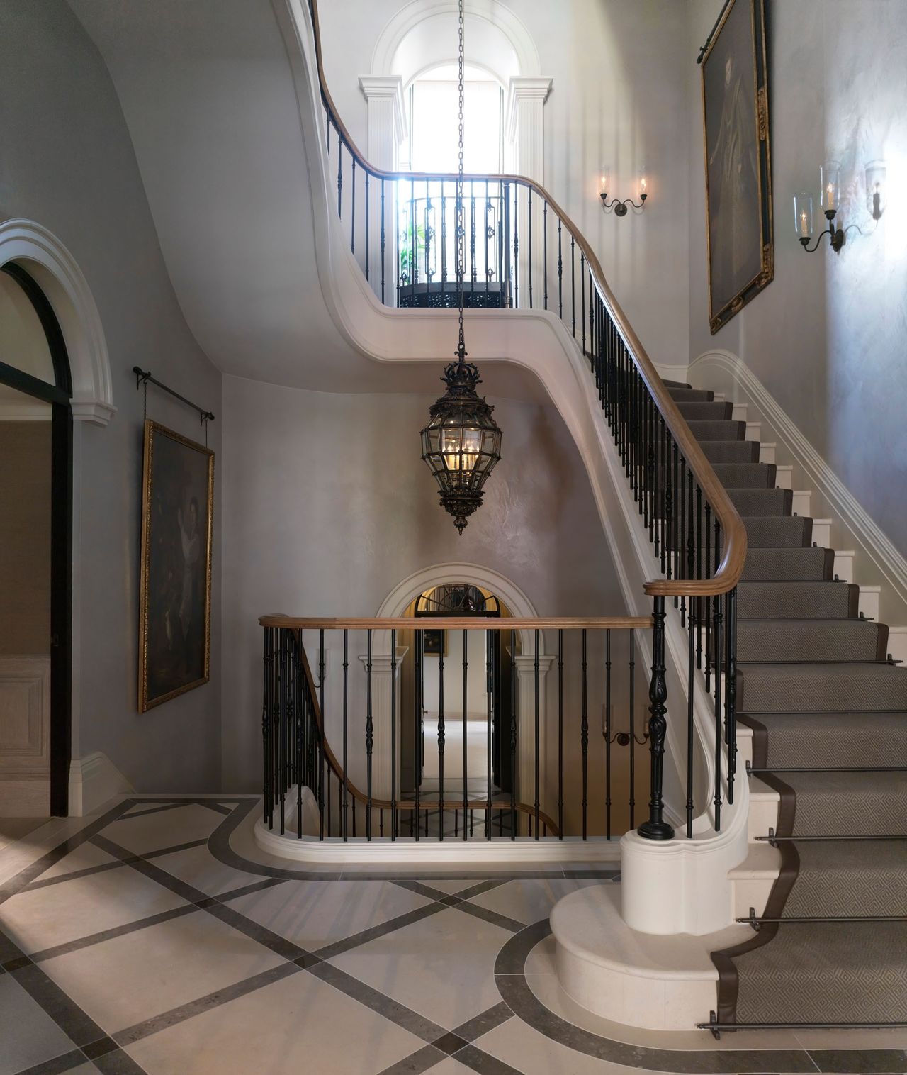 Open and light stairway with white and grey staircase and marble flooring. Glass chandler