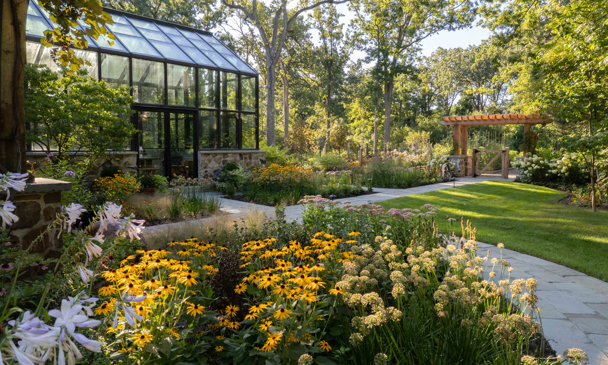Yellow black-eyed susan and other fall flowers with black conservatory to the rear