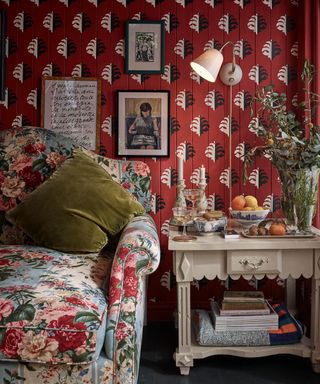 living room with red patterned wallpaper, wall light and floral sofa
