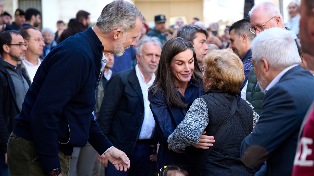 King Felipe and Queen Letizia of Spain hugging flood victims in a crowd of people