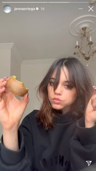 Jenna Ortega eating a kiwi like an apple.