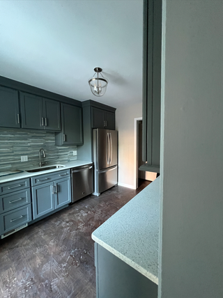 A kitchen with hardwood floor and dark grey cabinets