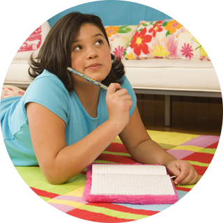 A pre-teen girl thoughtfully rests a pencil against her cheek as she decides what to write