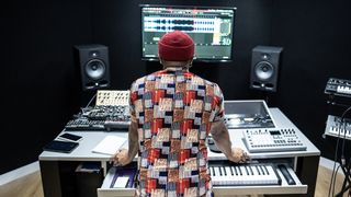 Man stands in front of his home studio equipment assessing his latest recording