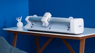 How to use a Cricut; a large craft machine on a desk next to a blue wall