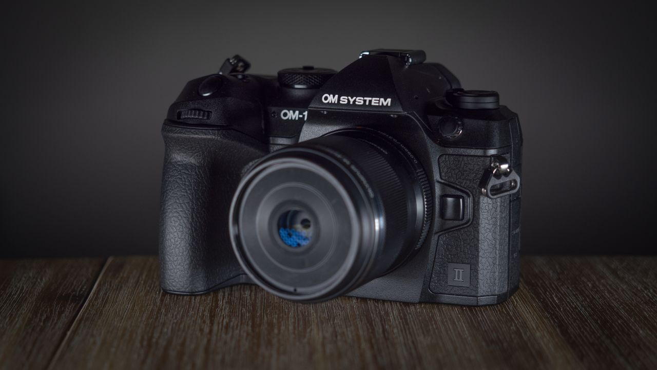 OM System OM-1 Mark II on a wooden surface, against a dark background