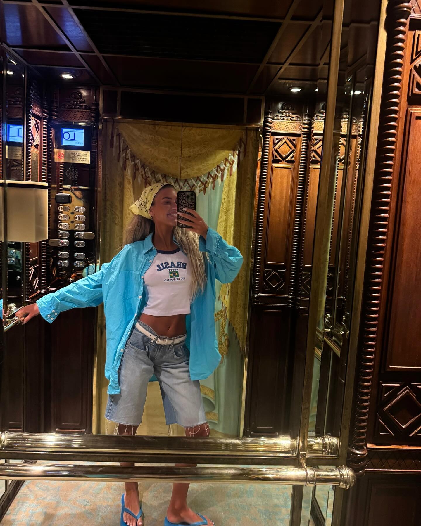 Woman in a blue shirt, jorts, and flip-flops