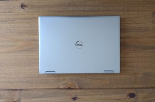 A silver Dell Inspiron 7620 2-in-1 laptop sitting on a wooden desk