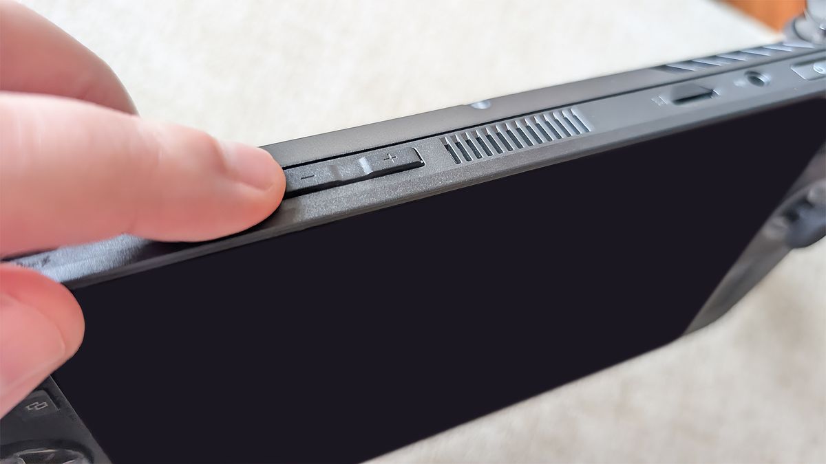 A finger tapping the volume down button on the Xbox Ally X.