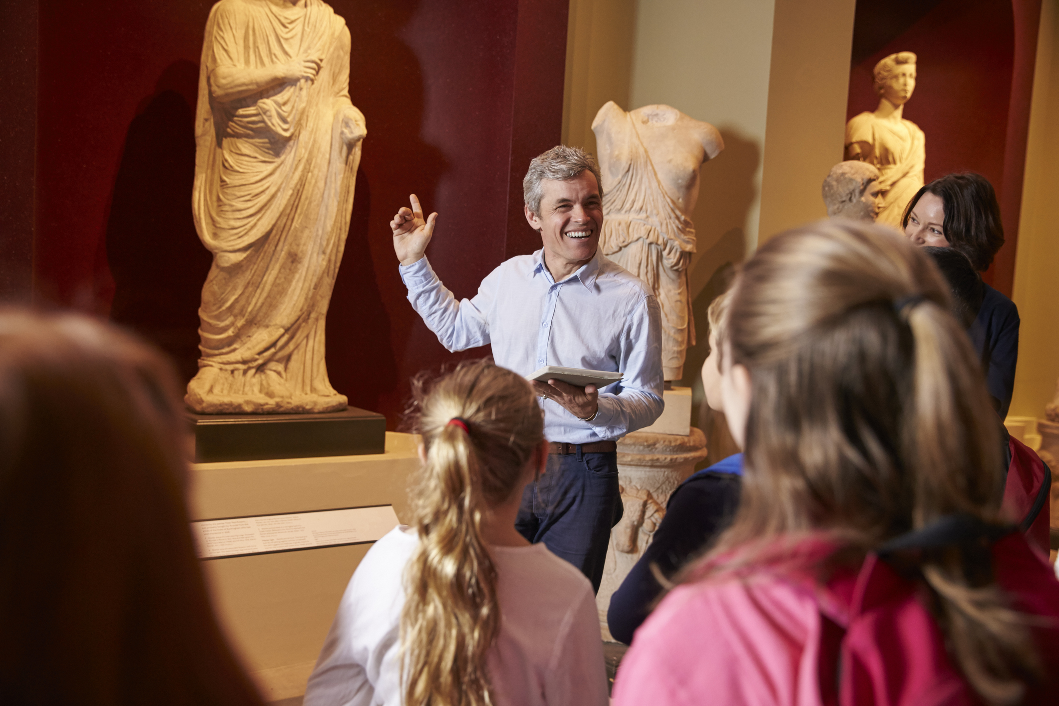 Pupils And Teacher On School Field Trip To Museum With Guide