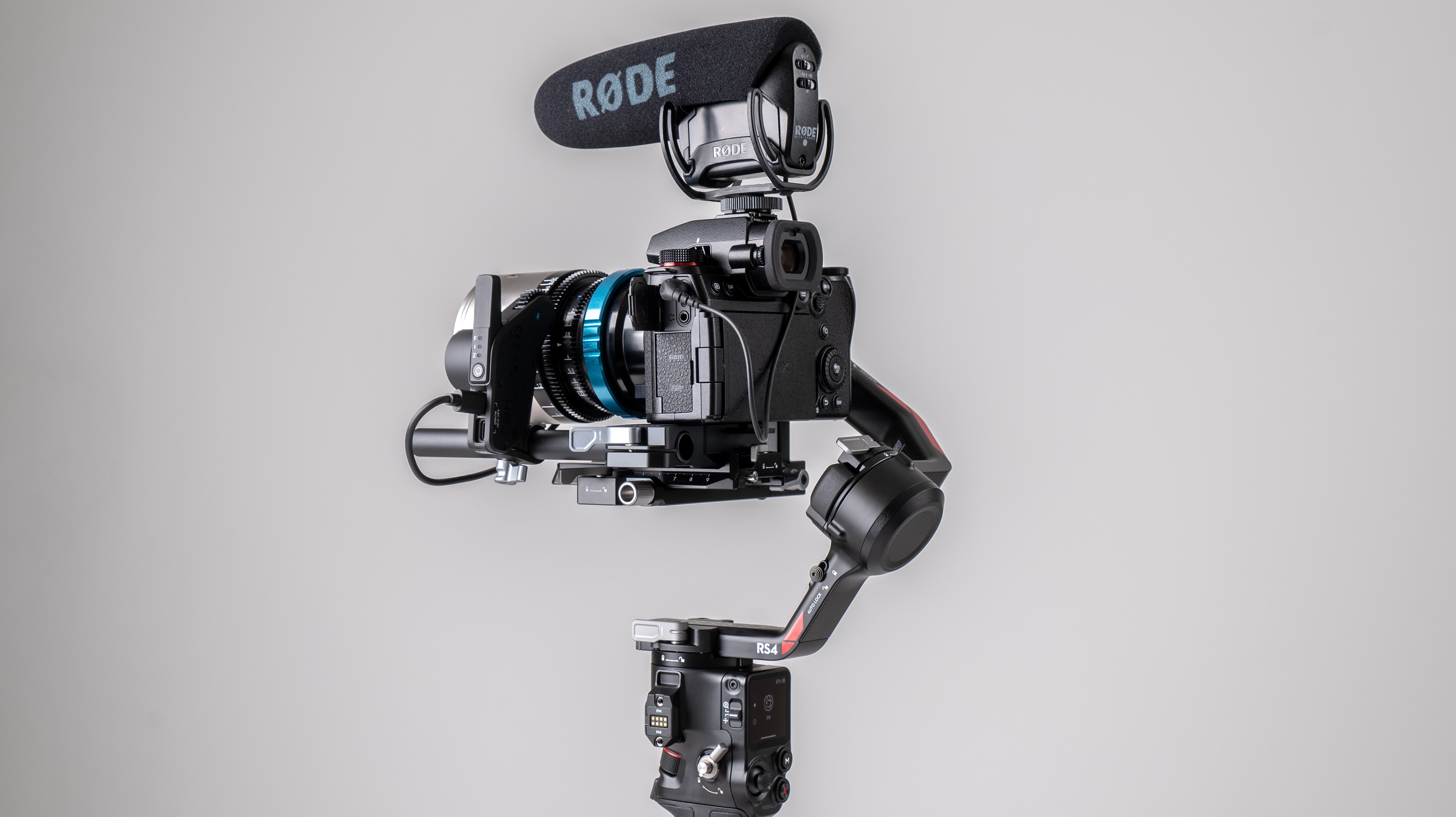 DJI RS 4 gimbal with Focus Pro system and Panasonic mirrorless camera on a off-white background