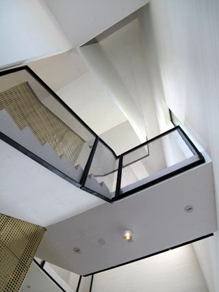 Hearning Museum of Contemporary Art by Steven Holl, Denmark. An upward view of a white staircase with glass railings and lights under it.