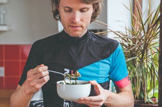 A male cyclist eating a bowl of food