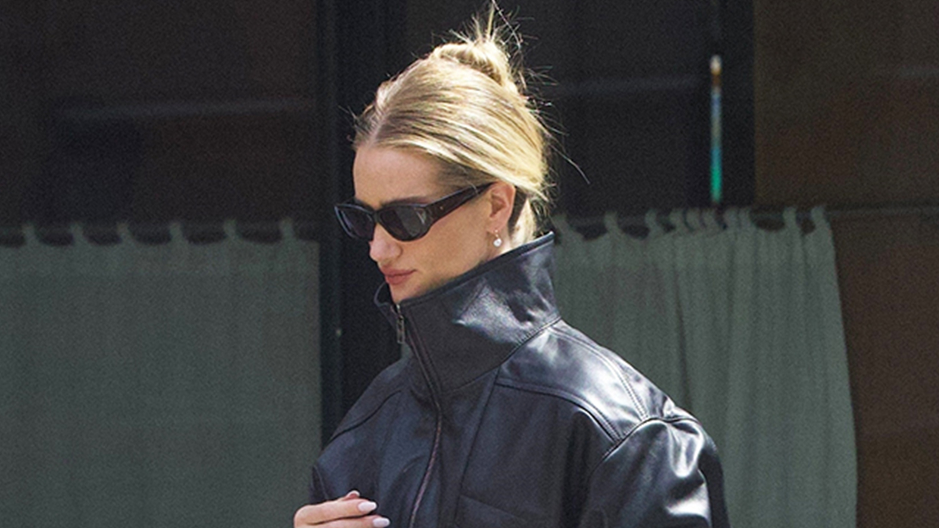 Rosie Huntington-Whiteley wearing a leather black jacket, white jeans, and black flip flops