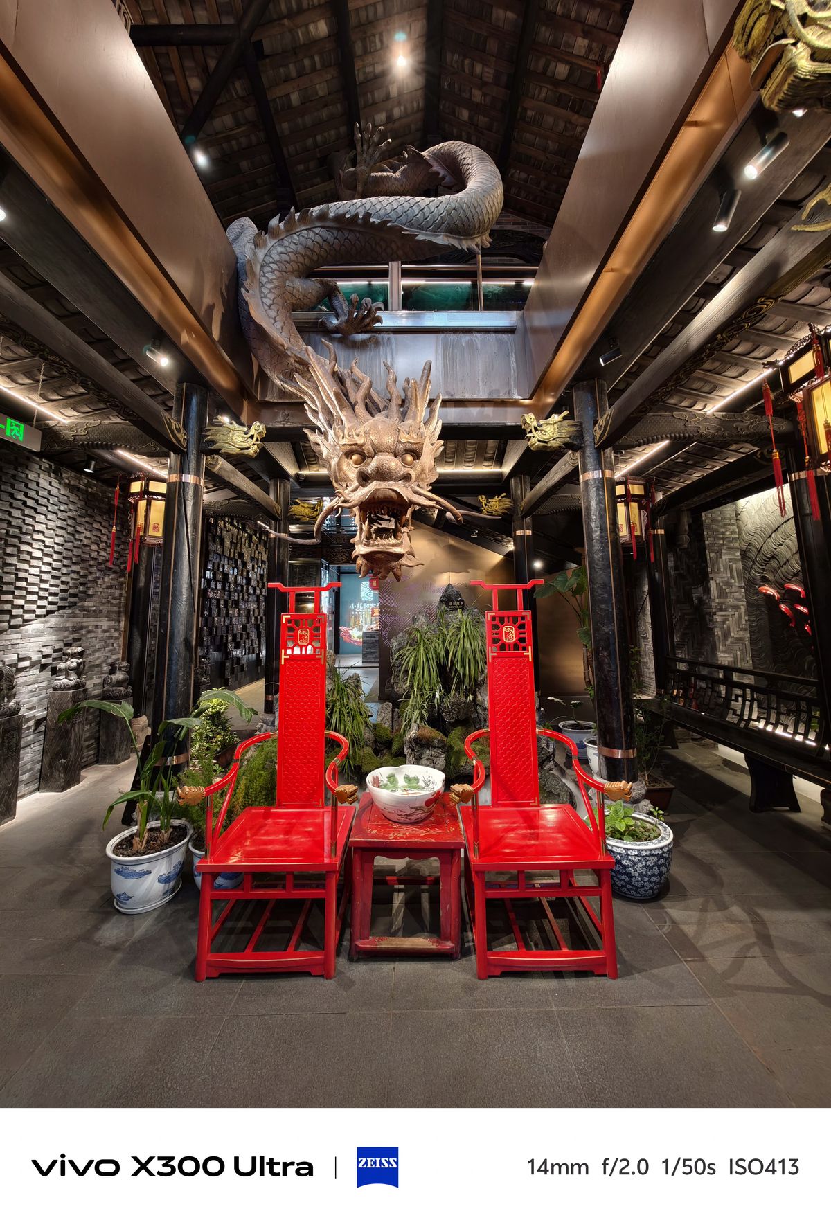 Two bright red chairs facing a table beneath a large, sculpted golden dragon on the ceiling.
