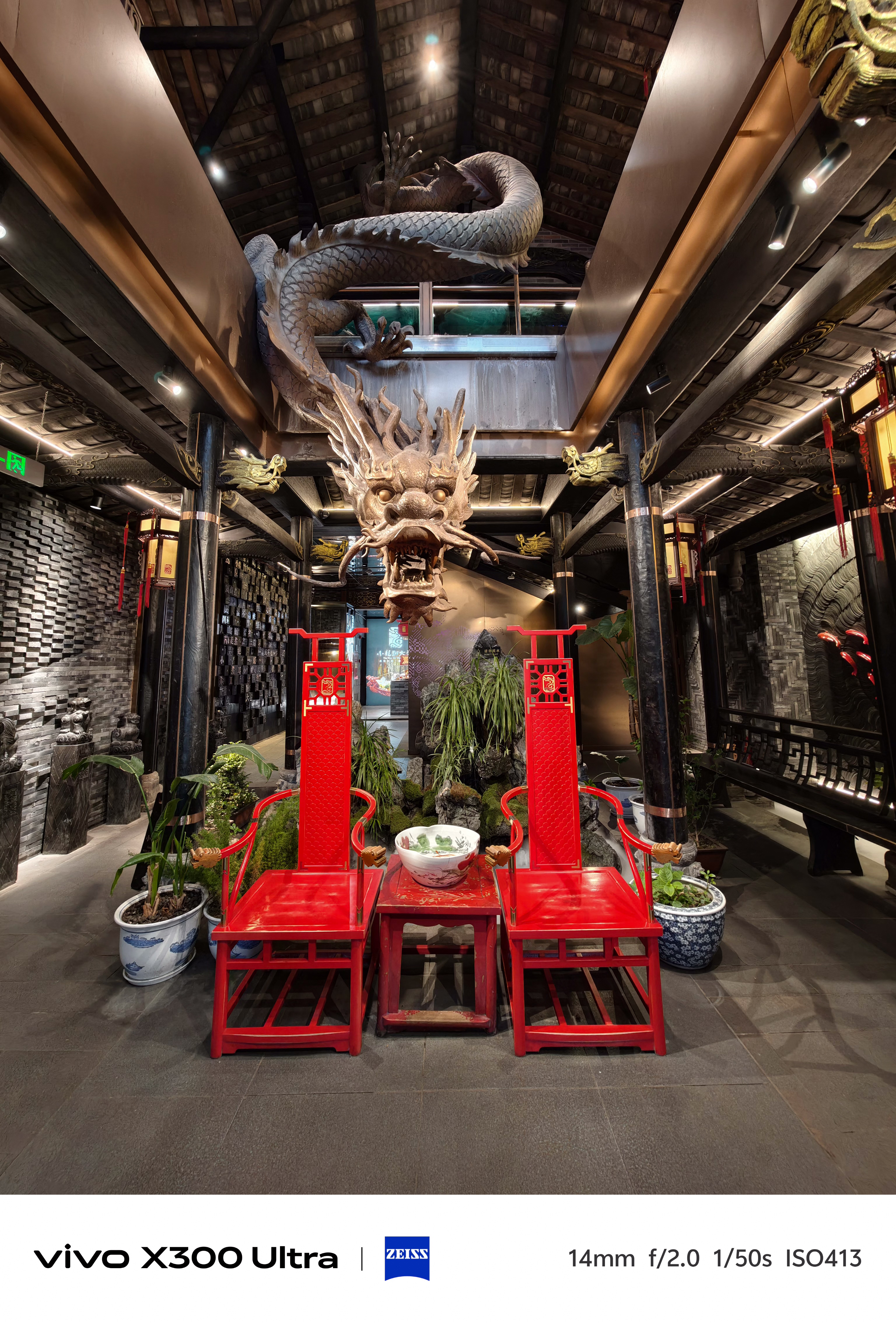Two bright red chairs facing a table beneath a large, sculpted golden dragon on the ceiling.
