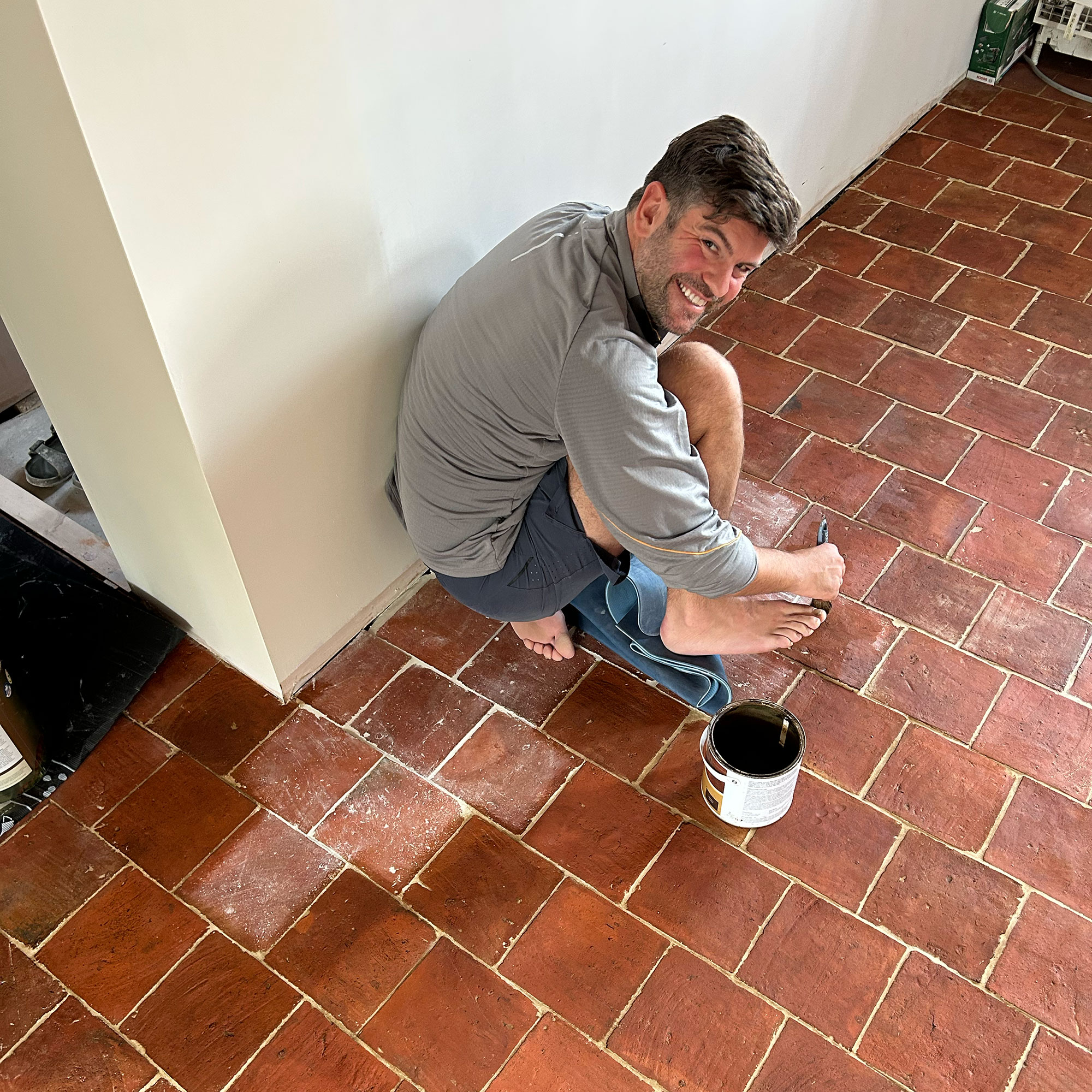 Man kneeling on floor sealing tiles