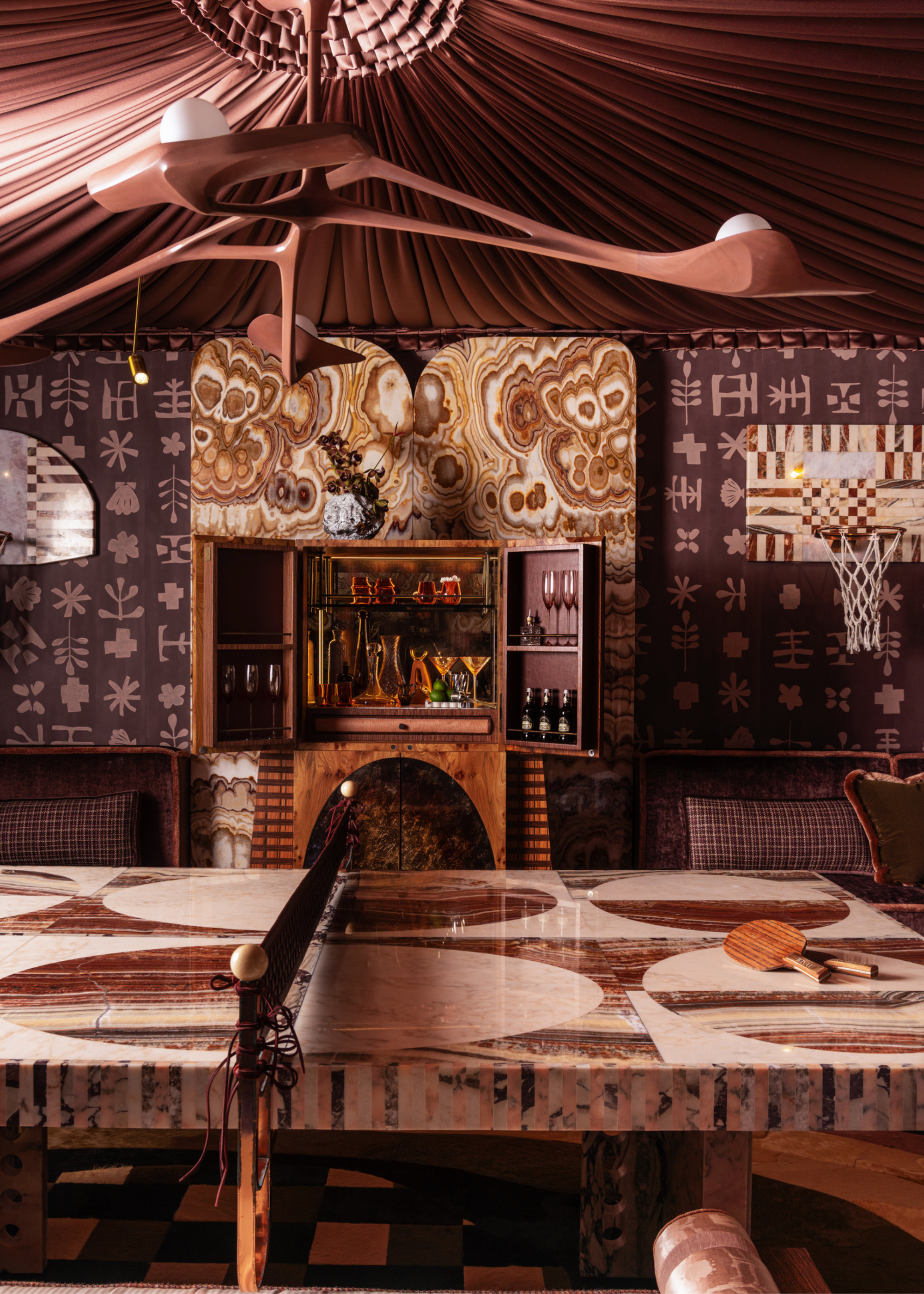 a maximalist-designed dark games room space with onyx ping pong table and basketball hoops