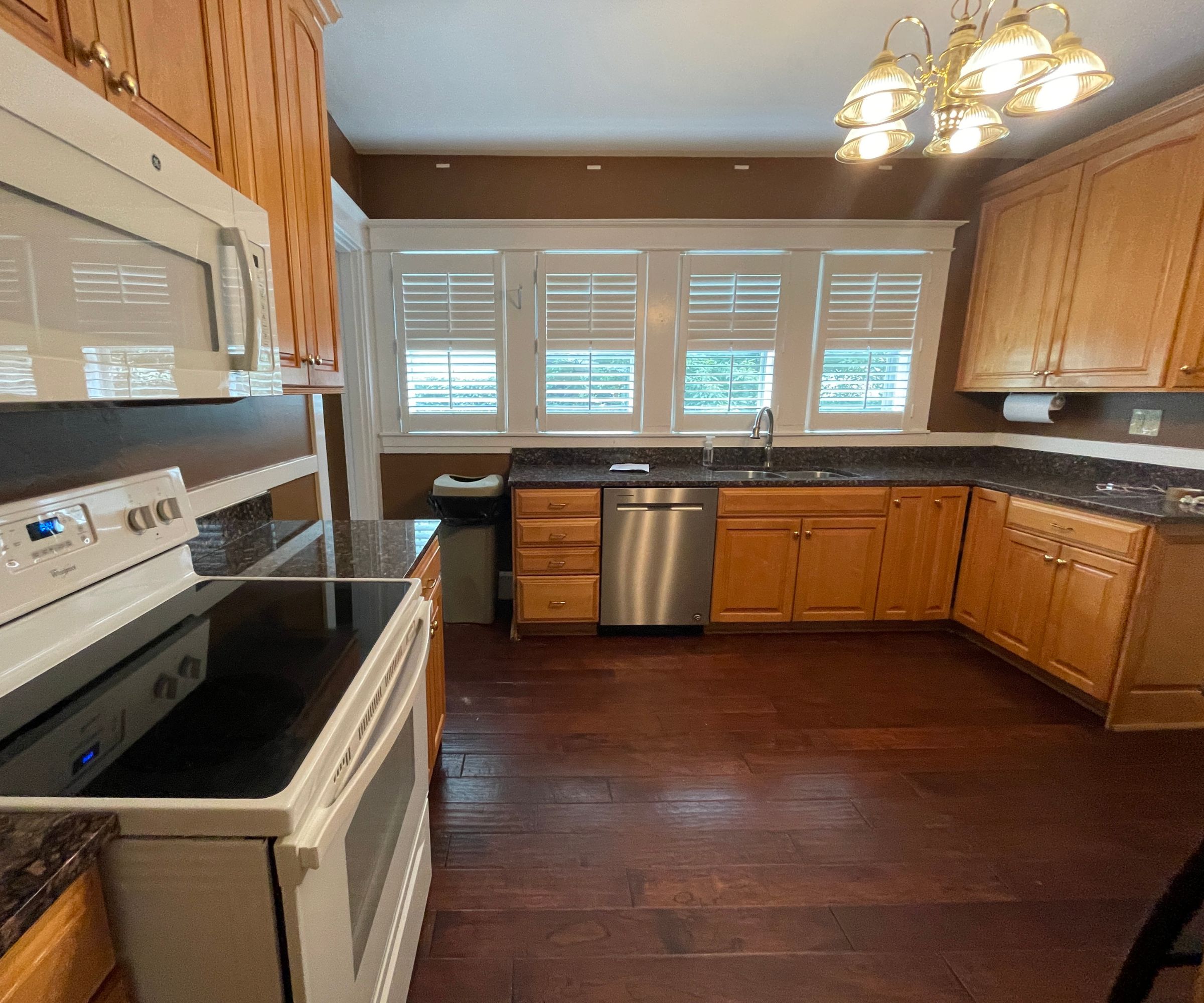A dated kitchen with orange pine cabinets and black countertops