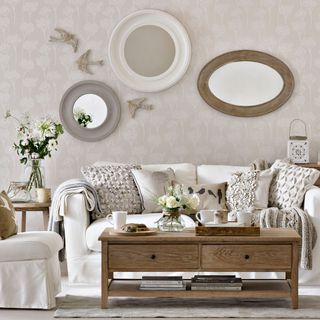 living area with wallpaper wall and white sofa and round mirrors