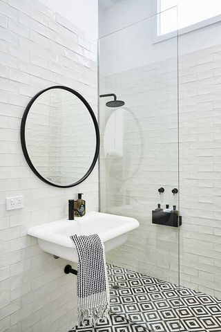 A mirror and sink in the bathroom with black and white tiles.