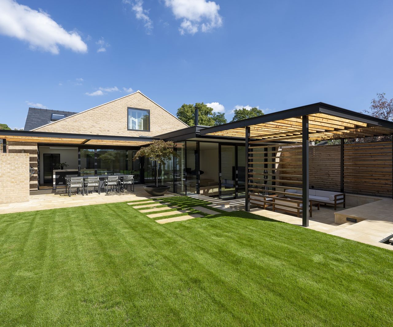 rear exterior of a renovated bungalow with covered patio area and fresh lawn