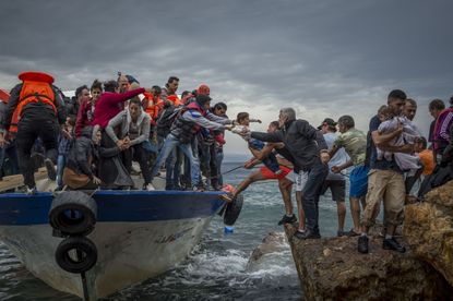 Refugees and Migrants aboard fishing boat drived by smugglers reach the Greek Island coast of Lesbos after crossing the Aegean sea from Turkey on October 11, 2015.