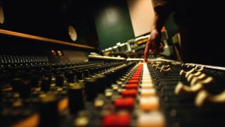 A man presses a button on a mixing console