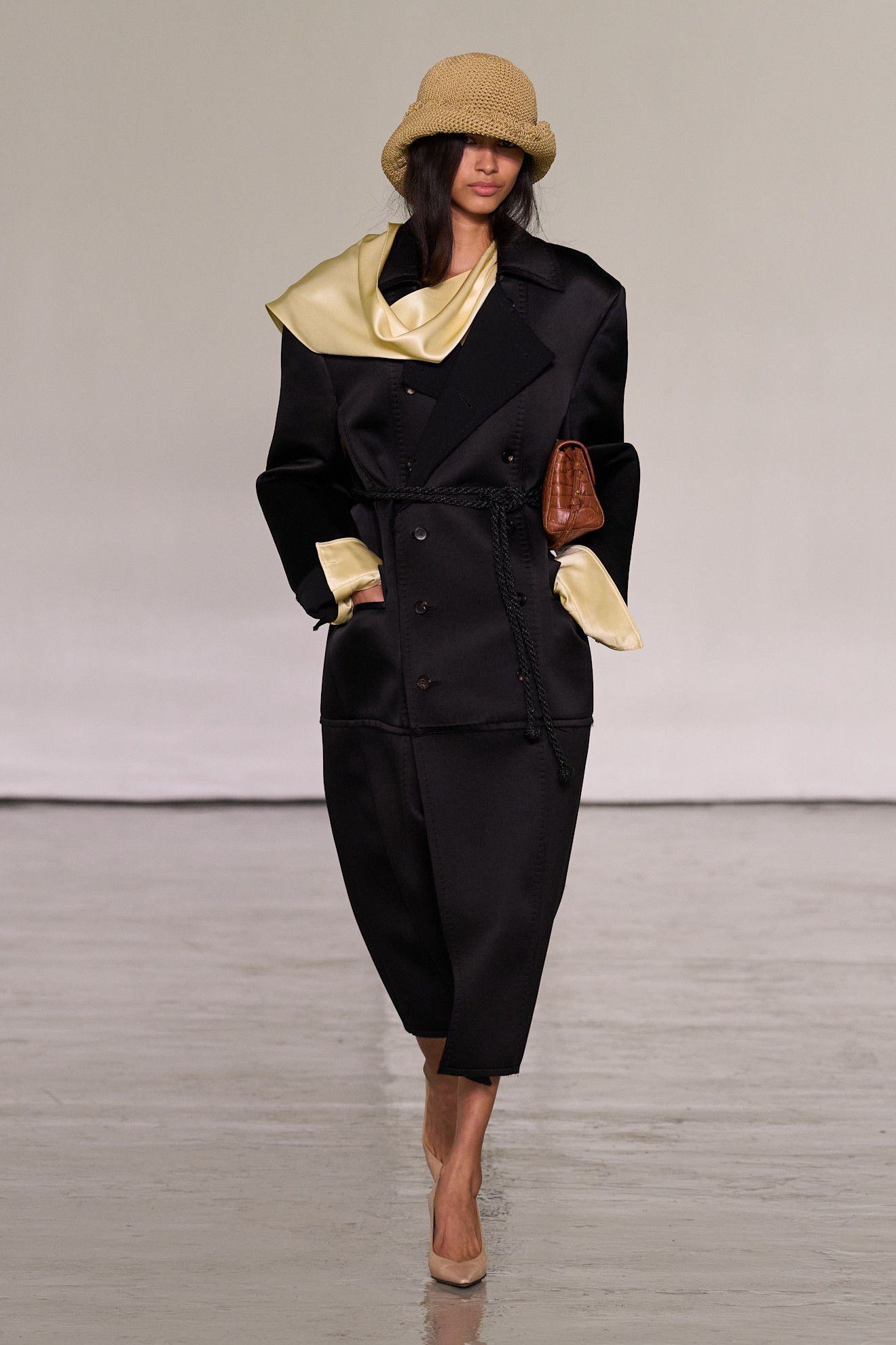 A model walking in the spring/summer 2027 Bottega Veneta show during Milan Fashion Week wearing a knit hat with a black coat.