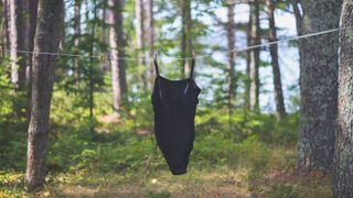 A black swimsuit hanging on a washing line illustrating how often should you wash swimwear