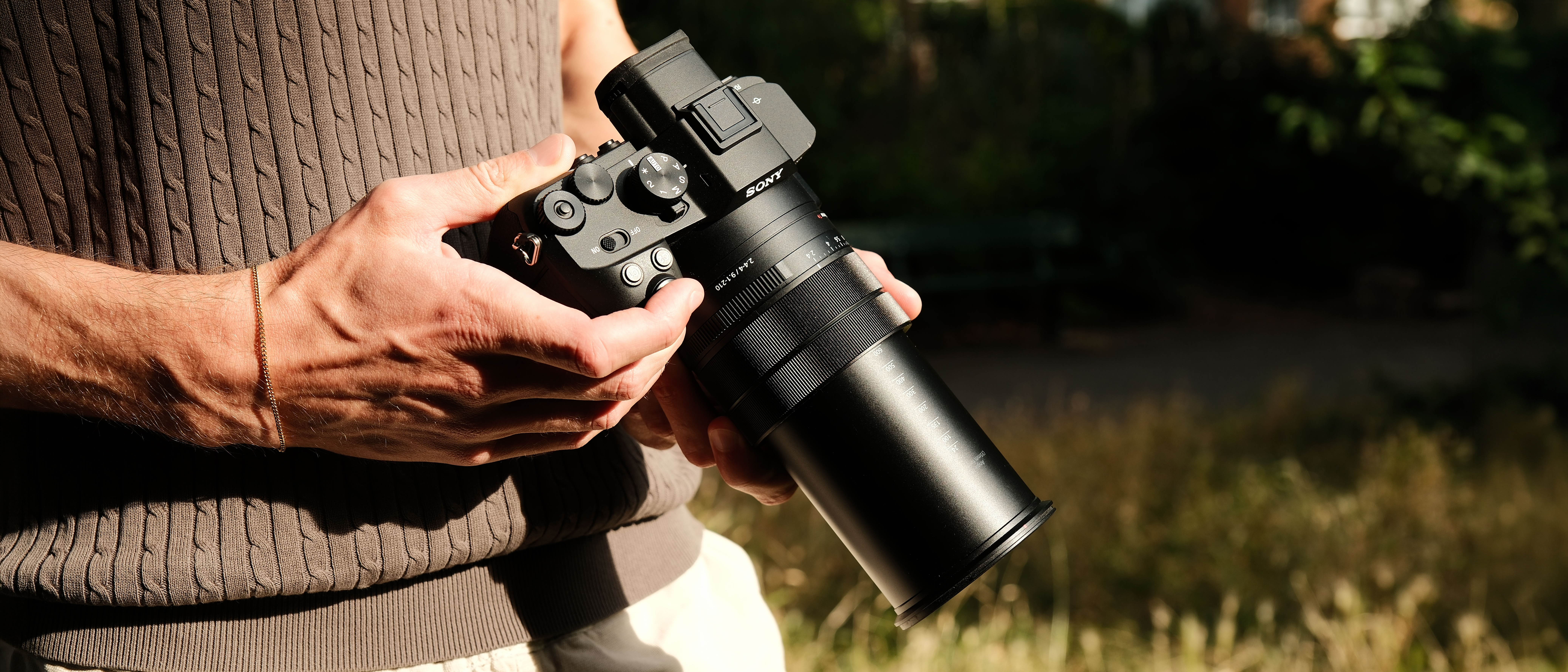 Photographer holding the Sony RX10 V bridge camera with its long zoom lens extended.